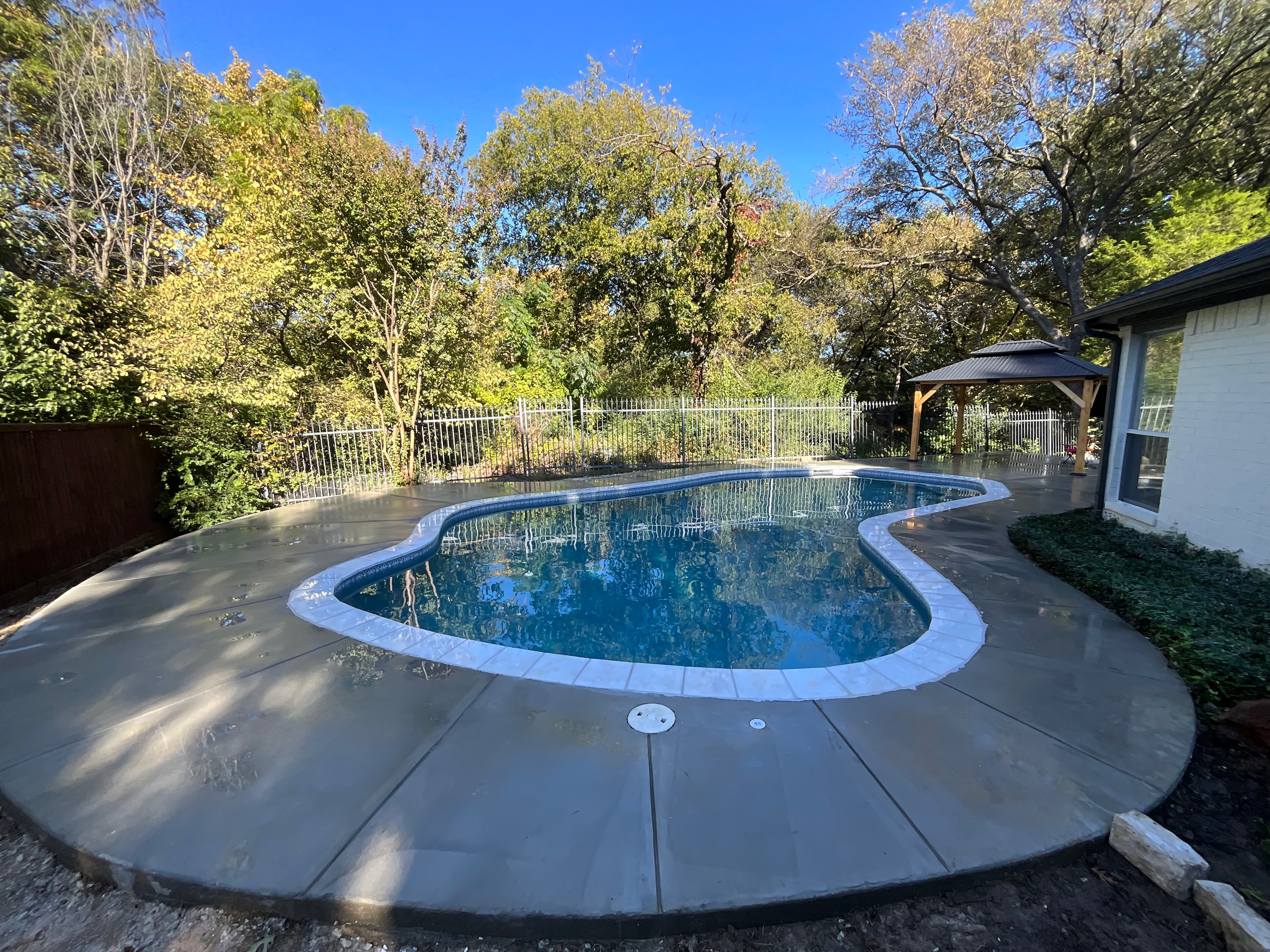 Freeform pool with gazebo and autumn trees