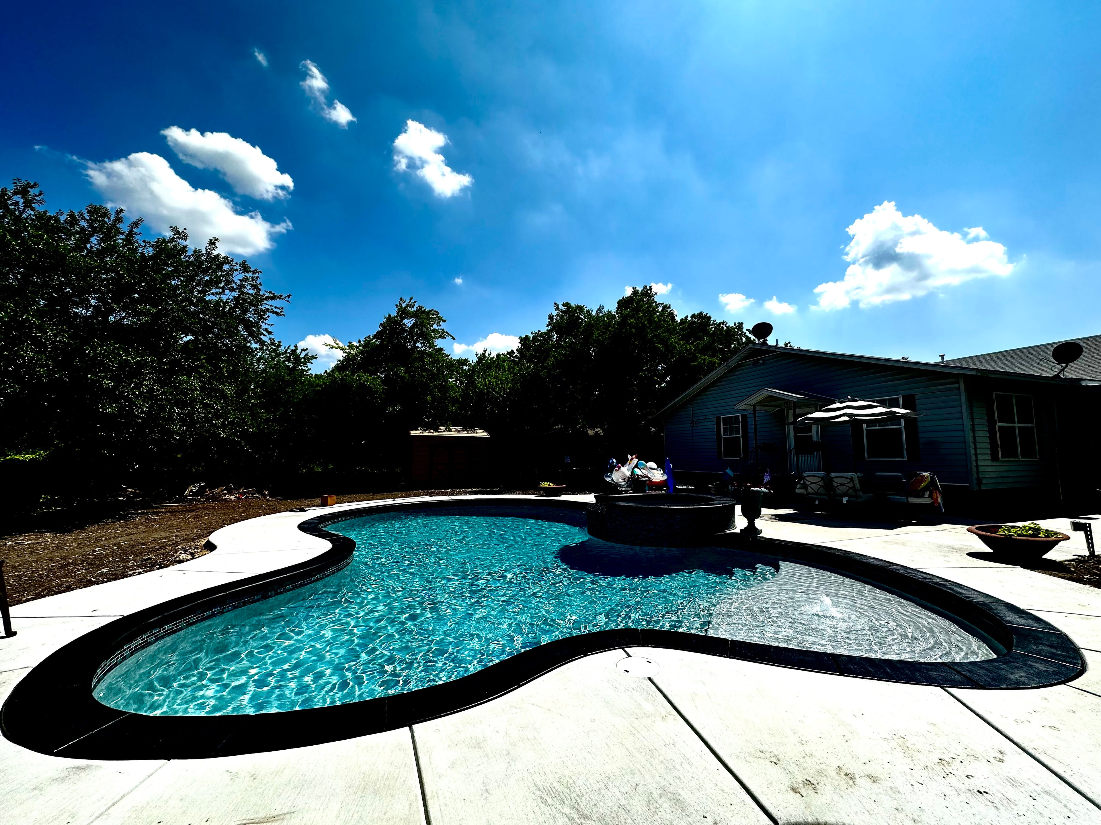 Freeform pool with spa and concrete deck