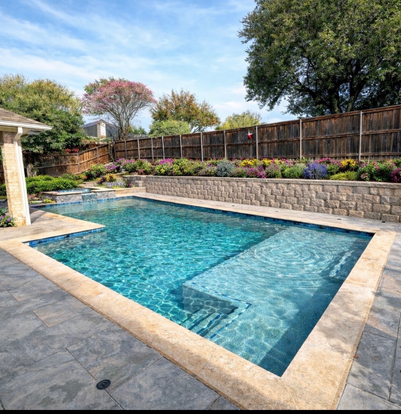 Texas backyard pool with stone retaining wall and landscaping